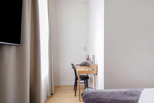 a bedroom with a desk with a chair next to a window at Best Western Hotel Baltic in Sundsvall