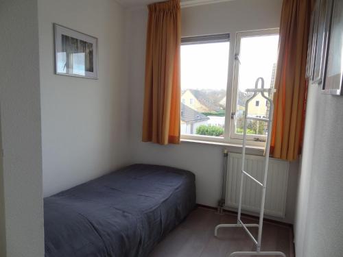 a small bedroom with a bed and a window at Holiday Home in Zeeland with Garden in Wemeldinge