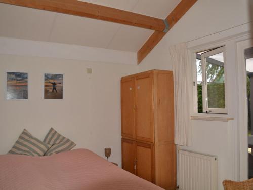 een slaapkamer met een bed, een kast en een raam bij Nice holiday home with sauna near beach in Wemeldinge