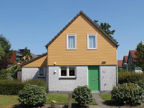 a house with a green door in a yard at Nice holiday home with sauna, in a holiday park only 200m away from the beach in Wemeldinge