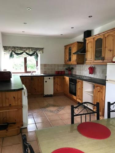 a kitchen with wooden cabinets and a table with a tableablish at Castlegregory-Seaside 2 Bedroomed Cottage in Castlegregory