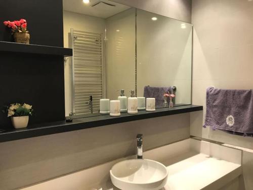 La salle de bains est pourvue d'un lavabo, d'un miroir et de serviettes pourpres. dans l'établissement mall of istanbul, à Basaksehir