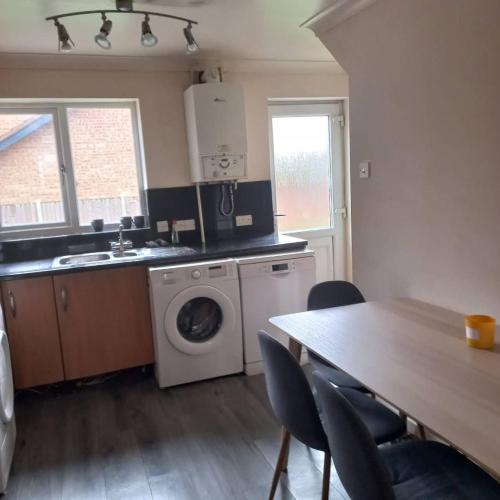 a kitchen with a washing machine and a table with chairs at hamilton 3 bedrooms 10 minutes from city centre in Leicester