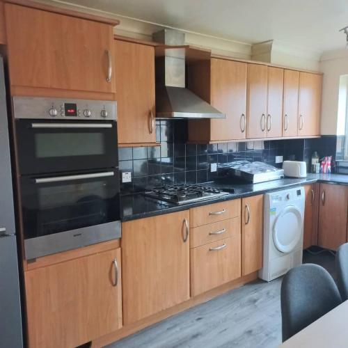 uma cozinha com armários de madeira e um forno com placa de fogão em hamilton 3 bedrooms 10 minutes from city centre em Leicester
