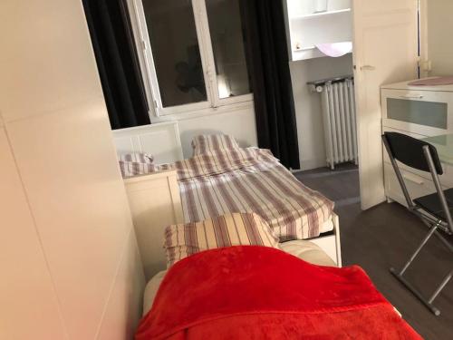 Habitación pequeña con cama con manta roja en Beau appartement,proche de métro en París