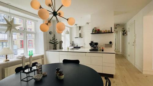 コペンハーゲンにあるApartmentInCopenhagen Apartment 1310のキッチン(黒いテーブル付)、白いキャビネット付きのキッチン