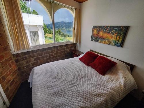 a bedroom with a bed and two windows at Refugio Génesis habitaciones Lago de Tota in Tota