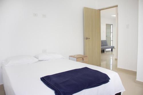 un letto bianco con una coperta blu sopra di APARTAMENTO VALLEDUPAR a Valledupar