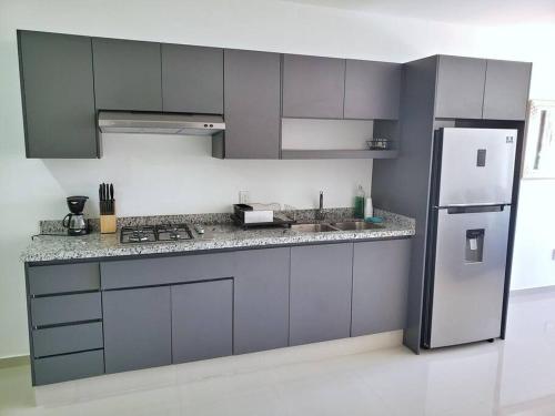 a kitchen with gray cabinets and a refrigerator at Departamento Siete Loft Sábalo in Mazatlán