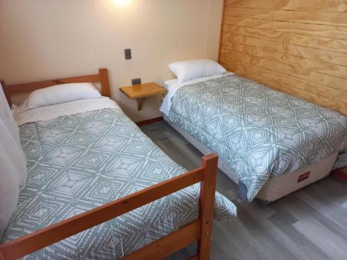 a room with two beds and a wooden floor at Agroturismo Coñico in Quilquico