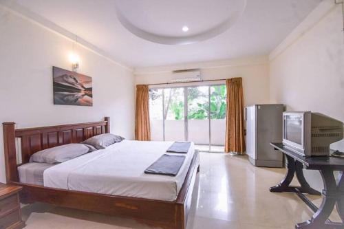 a bedroom with a bed and a desk with a television at We Residence in Pattaya Central