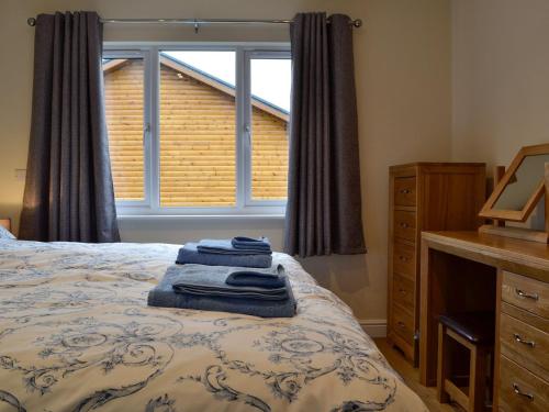 a bedroom with a bed with a dresser and a window at Bluebell Lodge in Llandrindod Wells