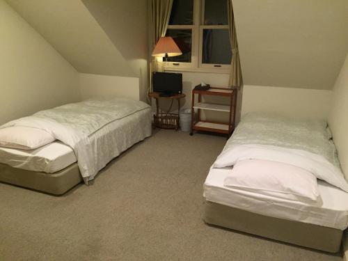 sypialnia z 2 łóżkami, telewizorem i oknem w obiekcie Guest House Bunk w mieście Myoko
