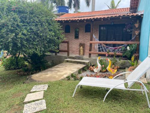 a yard with a white chair and a house at Hospedagem Recanto das Orquideas in Quatis