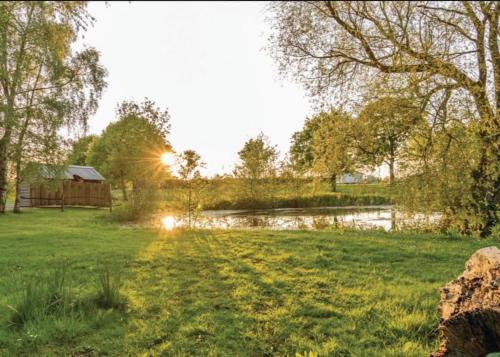 a field with a pond and a barn in the background at Barlings Country Park in Langworth