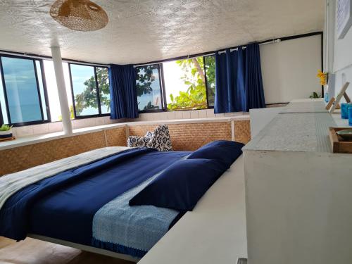 a bedroom with a large bed with blue sheets at The Hut Koh Mak Sea View in Ko Mak