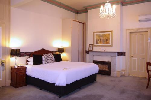 a bedroom with a large bed and a fireplace at The Hotel Shamrock in Bendigo