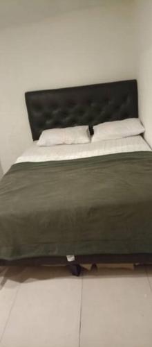 1 cama con edredón verde y sábanas blancas en N7 7 Habitación con Baño Privado y Kitchenette, en Montevideo