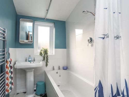 ein Badezimmer mit einer weißen Badewanne, einem Waschbecken und einer Badewanne in der Unterkunft 14 Rose Hill in Beaumaris