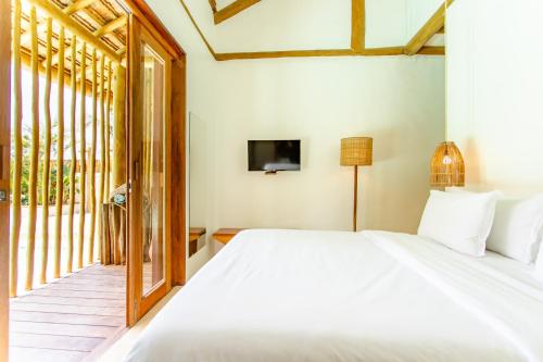 a bedroom with a white bed and a window at Café Jeri Hotel - Adults Only in Jericoacoara