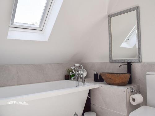 a bathroom with a white tub and a mirror at Leofric Lodge in Bampton