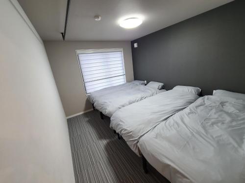 two beds in a small room with a window at パーリーフラッツ品川高輪台 PEARLY FLATS Shinagawa Takanawadai in Tokyo