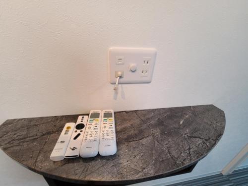 three remote controls sitting on a table next to a lightswitch at パーリーフラッツ品川高輪台 PEARLY FLATS Shinagawa Takanawadai in Tokyo