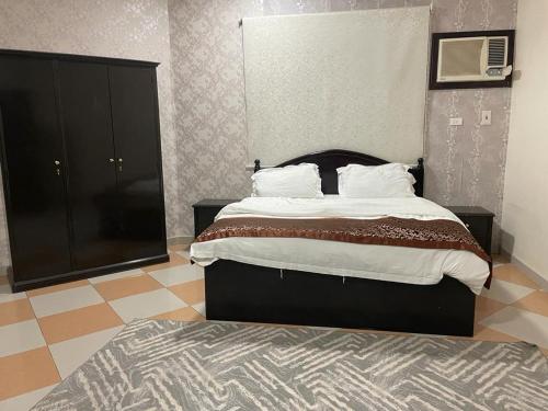 a bedroom with a large bed and a black cabinet at نزيل للشقق المفروشة in Taif