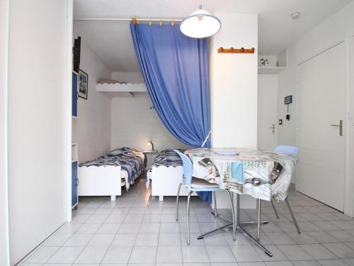 une chambre avec deux lits, une table et des chaises dans l'établissement Charmant T1 avec Loggia au Sud, Calme, Près Centre-Ville, Garage, Bien Équipé - FR-1-553-58, à Balaruc-les-Bains
