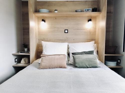a bedroom with a bed with a wooden headboard and pillows at Mobil-Home Jullouville, 2 pièces, 2 personnes - FR-1-361A-24 in Jullouville-les-Pins