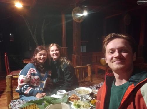 a group of people sitting at a table with food at Thao Ly Homestay Mai Chau in Hòa Bình