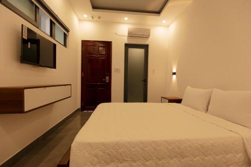 - une chambre avec un lit blanc et une télévision dans l'établissement Cassie Boutique Hotel, à Vung Tau