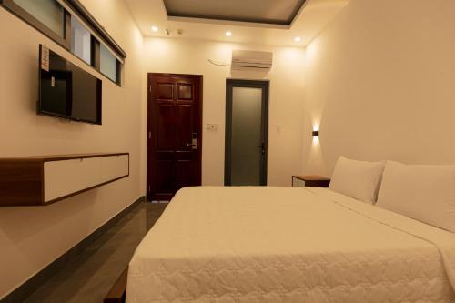 a bedroom with a white bed and a tv at Cassie Boutique Hotel in Vung Tau