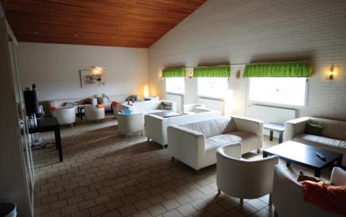 una sala de estar con sofás blancos, mesas y ventanas en Breviken Motel, en Brevik