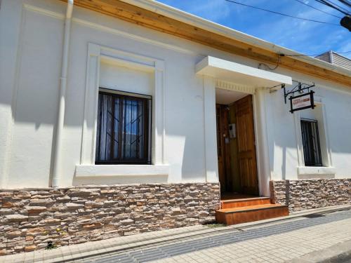 un edificio blanco con puerta y pared de piedra en Hospedaje Ahumada, en Constitución