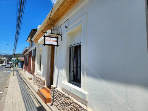 een wit gebouw met een bord aan de straatkant bij Hospedaje Ahumada in Constitución