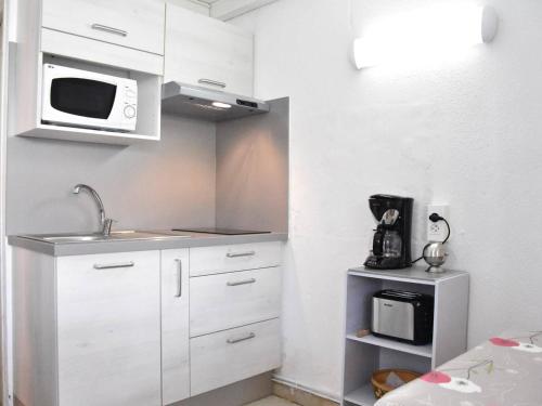 une petite cuisine avec un évier et un micro-ondes dans l'établissement Maison avec Piscine, Mezzanine et Climatisation - 5 Couchages - Gruissan - FR-1-229-821, à Gruissan