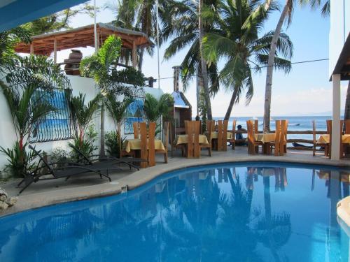 a swimming pool with tables and chairs and the ocean at Montani Beach Resort Puerto Galera powered by Cocotel in Puerto Galera