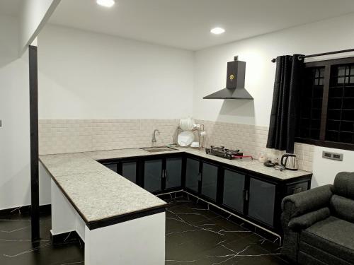 uma cozinha com um balcão, um lavatório e um sofá em La casa de Alexa homestay em Idukki
