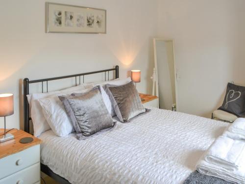 a bedroom with a bed with white sheets and pillows at Crescent By The Sea in Newbiggin-by-the-Sea