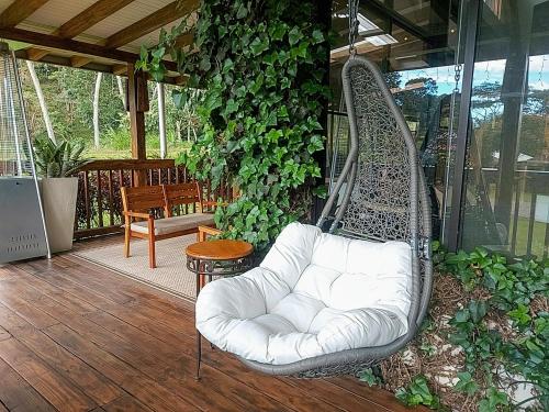 a white swinging chair on a porch with plants at The Riverside Inn in Boquete