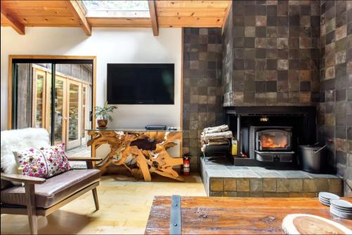 a living room with a fireplace and a tv at Sur Grove Big Sur in Big Sur