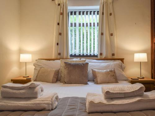 a bedroom with a large bed with towels on it at Magnolia Cottage in Ratley
