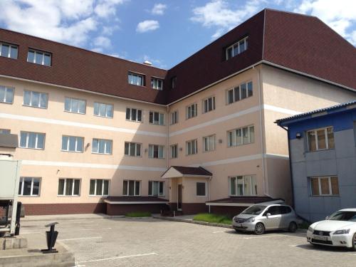 un grand bâtiment avec des voitures garées dans un parking dans l'établissement Dvorik Hotel, à Krasnoïarsk