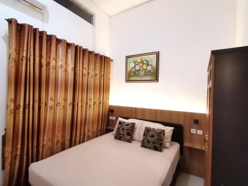 ein kleines Bett in einem Zimmer mit Vorhängen in der Unterkunft Villa Asri in Batu