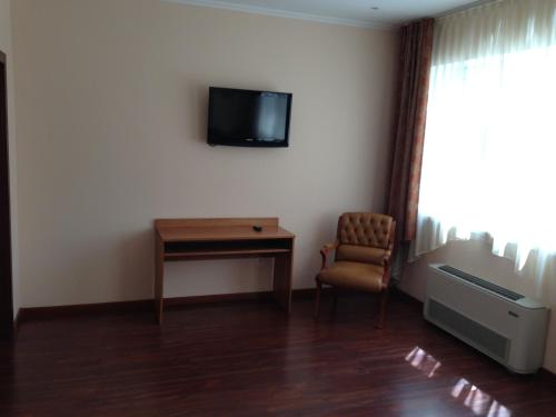 a room with a desk and a tv and a chair at Dvorik Hotel in Krasnoyarsk