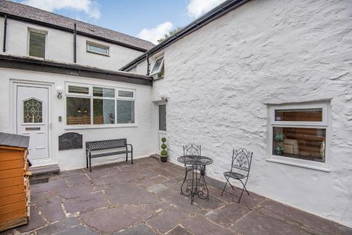 a patio with a table and chairs next to a building at Bwthyn Y Nant in Dinorwic