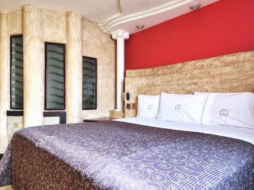 a bedroom with a large bed with a red wall at Motel Atenas in Puebla