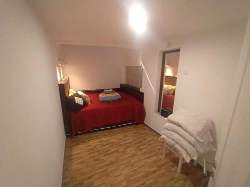 een kleine slaapkamer met een rood bed en een spiegel bij Ginjals 67 in Almargem