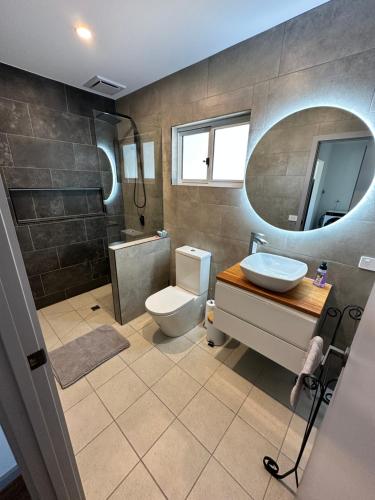 a bathroom with a toilet and a sink and a mirror at Luxury Holiday Unit 8min walk to Town Center with Boat Parking in Mallacoota